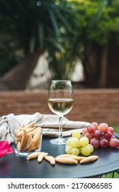 A Glass Of White Wine With Appetizers On The Table.