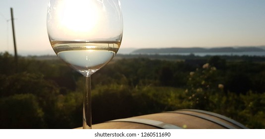 A Glass Of White Wine, With The Lake Balaton In The Background.