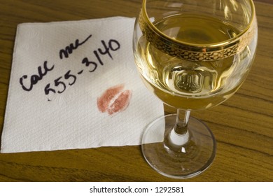 Glass Of White Wine And A Napkin With Phone Number And Lipstick