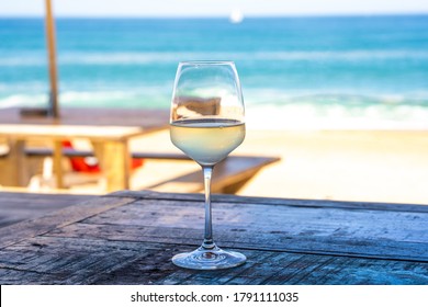 A Glass Of White Wine On Wooden Table Of Outdoor Restaurant On The Beach. Sea View. Summer Beach Vacation. 