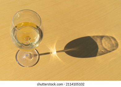 Glass of white wine on yellow  background with sunshine shadow effect and empty copy space