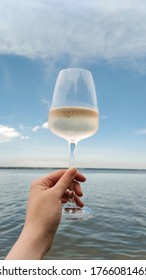 Glass Of White Wine In Woman Hand Against The Blue Sky And Sea. Relax Summer