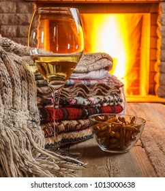 Glass Of White Wine; And Wool; Things Against Cozy Fireplace Background; Winter Vacation; Horizontal; Closeup; Selective Focus. 