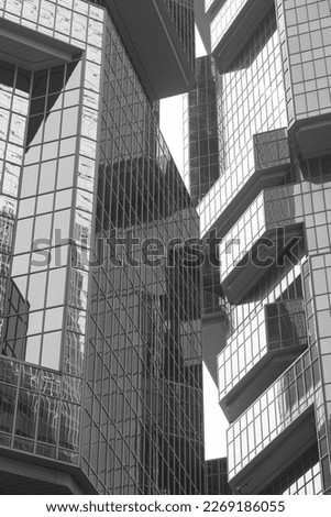 Glass windows of contemporary business building with reflection close-up. Modern architecture with sun rays - Monochrome