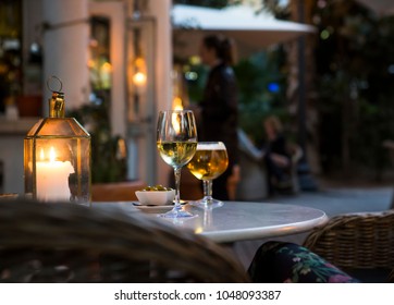 A glass of wine and beer with olives on a table at a cozy restaurant.
