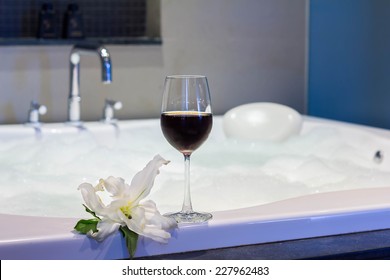 Glass of wine beside bathtub with flower. - Powered by Shutterstock