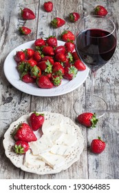 glass of wine, cheese and fresh strawberries on wooden table