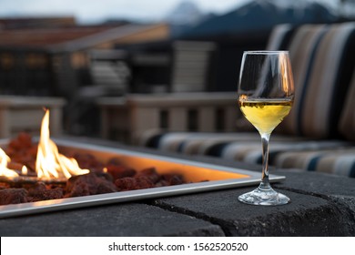 Glass of wine next to an outdoor fire pit and furniture￼