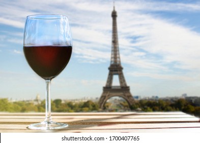 Glass of wine on Eiffel tower blur background. Sunny view of glass of red wine overlooking the Eiffel Tower in Paris, France - Shutterstock ID 1700407765