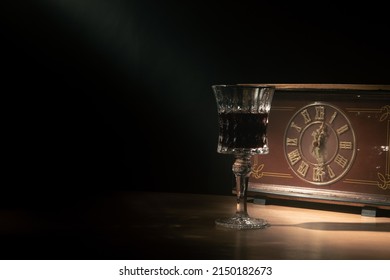 A Glass Of Wine With A Vintage Clock In A Narrow Beam Of Light And Smoke