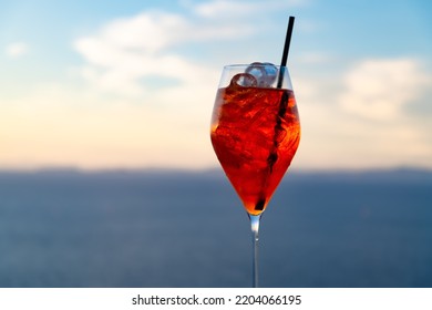 Glass Of Wine-based Cocktail, Served As An Aperitif In Capri Italy. It Consists Of Prosecco, Digestive Bitters And Soda Water. Intense Orange Drink Backlit By Sunlight With Straw And Icecubes.