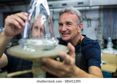 Glassblower and a colleague examining glassware at glassblowing factory - Powered by Shutterstock