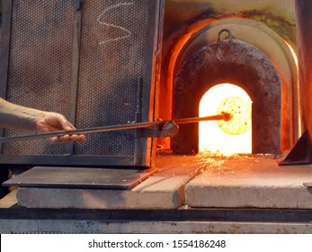 A Glassblower Makes A Vase Of Glass In A Manufactory On The Island Of Murano, Venice, Italy. Crucible Furnace.