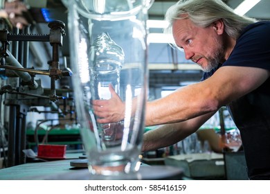 Glassblower working on a glass at glassblowing factory - Powered by Shutterstock