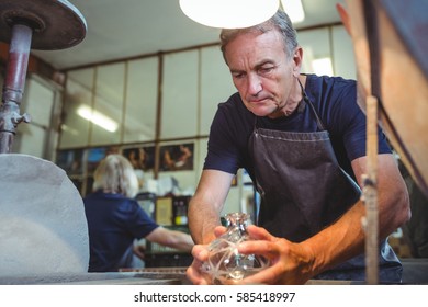 Glassblower working on a glass at glassblowing factory - Powered by Shutterstock