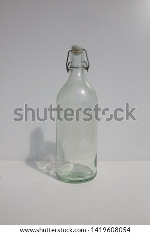 a glassbottle agains a white background With shadows in the sunlight
