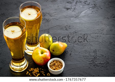 Glasses of beer with apple and peer on black table copy space