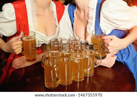 A lot of glasses of beer between the breasts of young girls on the holiday Oktoberfest