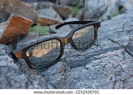 Glasses in black frame placed on a mountain rock surface, representing strength and durability 