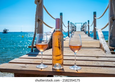 Glasses And Bottle Of Cold Rose Wine From Provence Served Outdoor On Wooden Yacht Pier With View On Blue Water And White Sandy Beach Plage De Pampelonne Near Saint-Tropez, Summer Vacation In France