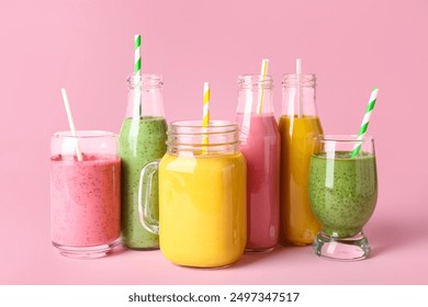 Glasses and bottles of different tasty smoothie with straws on pink background - Powered by Shutterstock