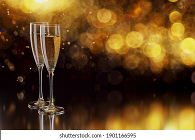 Glasses with champagne and copy space for text on blurred yellow lights.