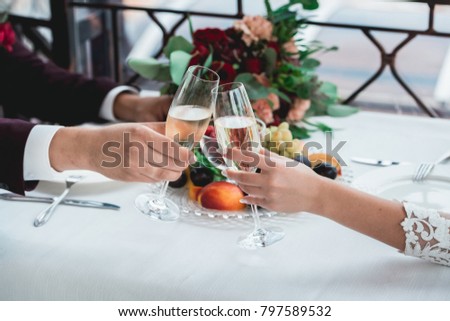 Glasses with champagne drink in bride and groom hands. Happy newlyweds drinking. Loving couple created new family.