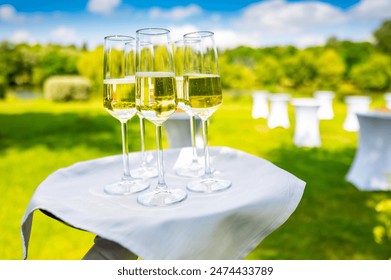 glasses of champagne on a tray at a garden party, with white tables in the blurred background. Ideal for events or celebrations - Powered by Shutterstock