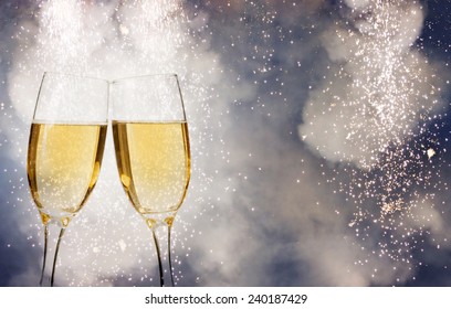 Glasses with champagne over fireworks and sparkling holiday background