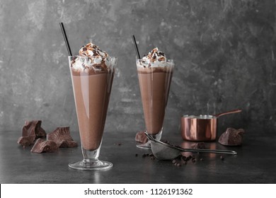 Glasses with chocolate milk shakes on grey table