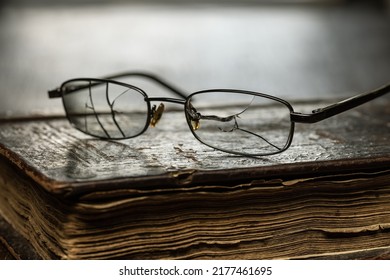 Glasses With Cracked Glasses On An Antique Book In A Leather Antique Binding, Studio Shot.	
