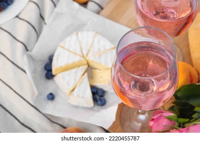 Glasses Of Delicious Rose Wine, Flowers And Food On White Picnic Blanket