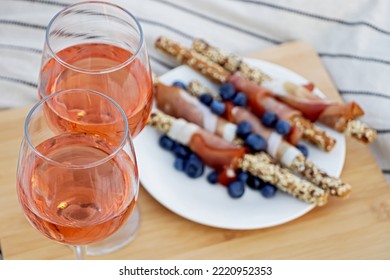 Glasses Of Delicious Rose Wine And Food On White Picnic Blanket, Closeup