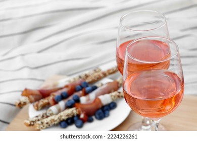 Glasses Of Delicious Rose Wine And Food On White Picnic Blanket, Closeup