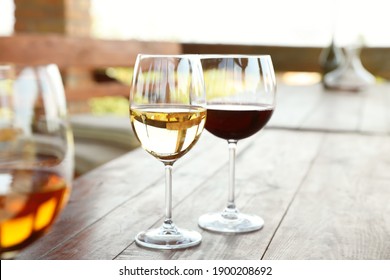 Glasses with different wines on wooden table in outdoor cafe - Powered by Shutterstock