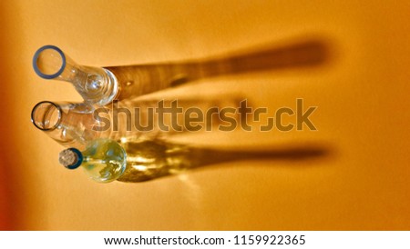 Glasses empty with shadows and reflection on the surface on a yellow background, place for text. Test glass flask in research laboratory. Science and medical background.