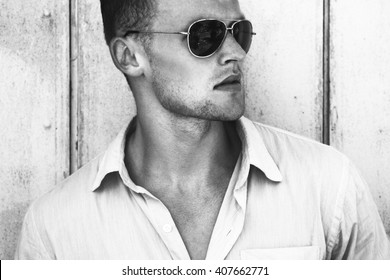 Glasses fashion beauty concept. Portrait of a young and handsome man in a white shirt and trendy glasses posing over wooden background. Close up. Street shot.