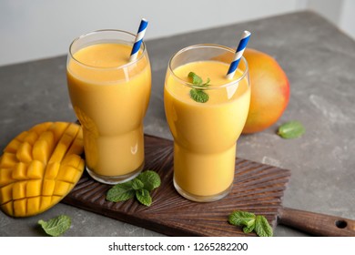 Glasses of fresh mango drink and fruits on table