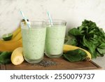 Glasses of fresh spinach smoothie with bananas and chia seeds on white background