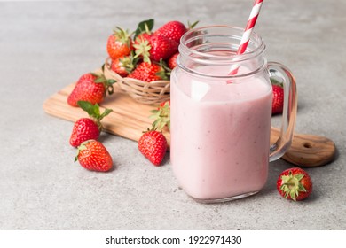 Glasses of fresh strawberry smoothie on a grey background. Summer drink shake, milkshake and refreshment organic concept.
