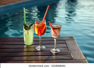 Glasses Of Fresh Summer Cocktails On Wooden Table Near Swimming Pool Outdoors