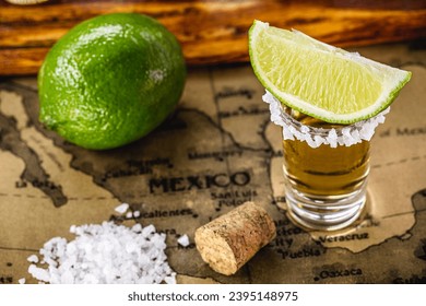 glasses of golden tequila, served with salt and lemon, over vintage map of mexico