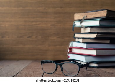 Glasses with hardback books on wooden table. Free space for text. Selective focus - Shutterstock ID 613718231