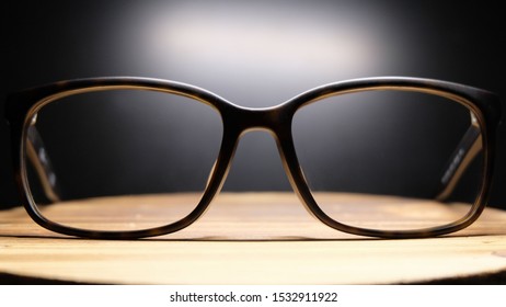 The glasses have black legs that shine through the eyepiece points on the wooden table. On a black background - Shutterstock ID 1532911922