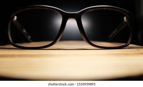The glasses have black legs that shine through the eyepiece points on the wooden table. On a black background - Shutterstock ID 1533939893