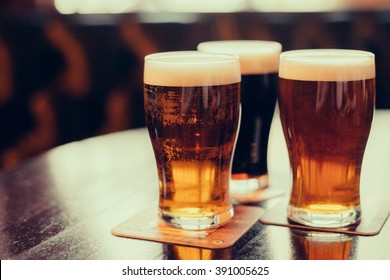 Бокалы светлого и темного пива на фоне паба.