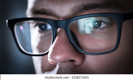 Glasses With Light Reflected From Computer Or Smartphone Screen. Thoughtful Business Man Or Focused Student Working Late At Night. Coder, Programmer Or Geek With Phone Or Laptop. Reflection Of Monitor