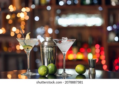 Glasses Of Margarita Cocktail, Limes And Shaker On Table In Bar