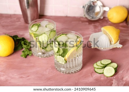 Glasses of mojito with cucumber on grunge pink table