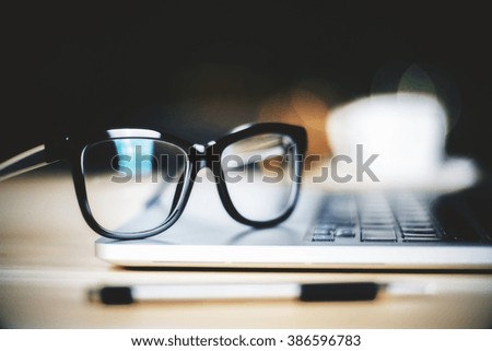 Glasses on laptop with pen, close up